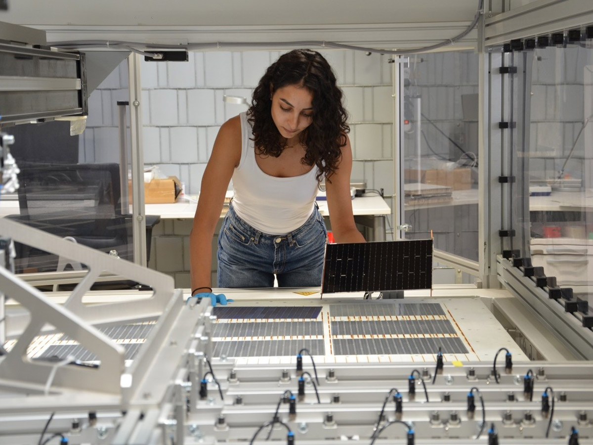 Die Projektleiterin am Fraunhofer ISE, Najwa Abdel Latif kontrolliert die verschalteten Solarzellen am Schindel-Matrix-Stringer des Fraunhofer ISE.